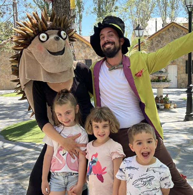 Monitor disfrazado y personaje infantil posando con niños en La Granja de los Cuentos.