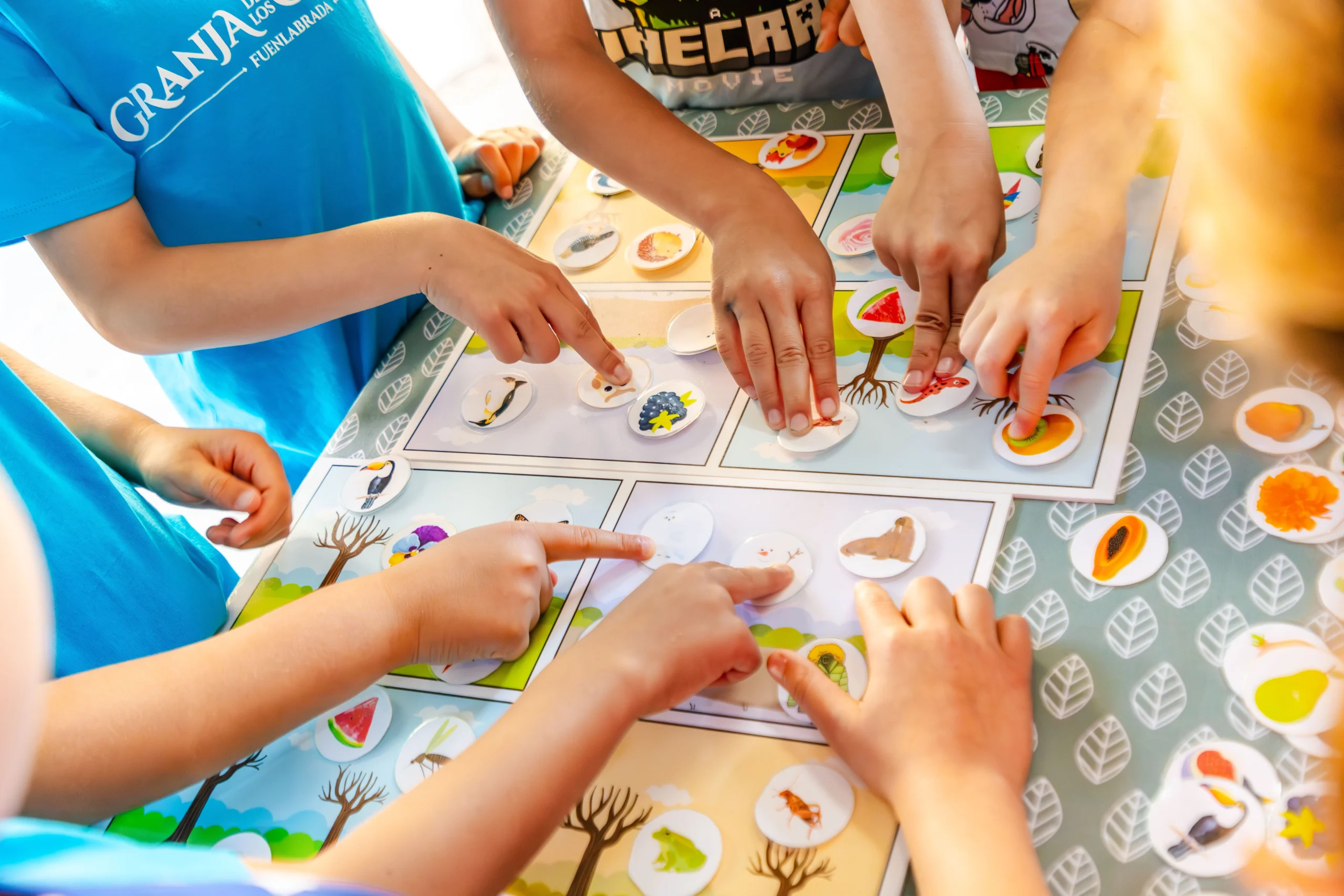 Manos de niños colocando fichas en una actividad educativa en La Granja de los Cuentos