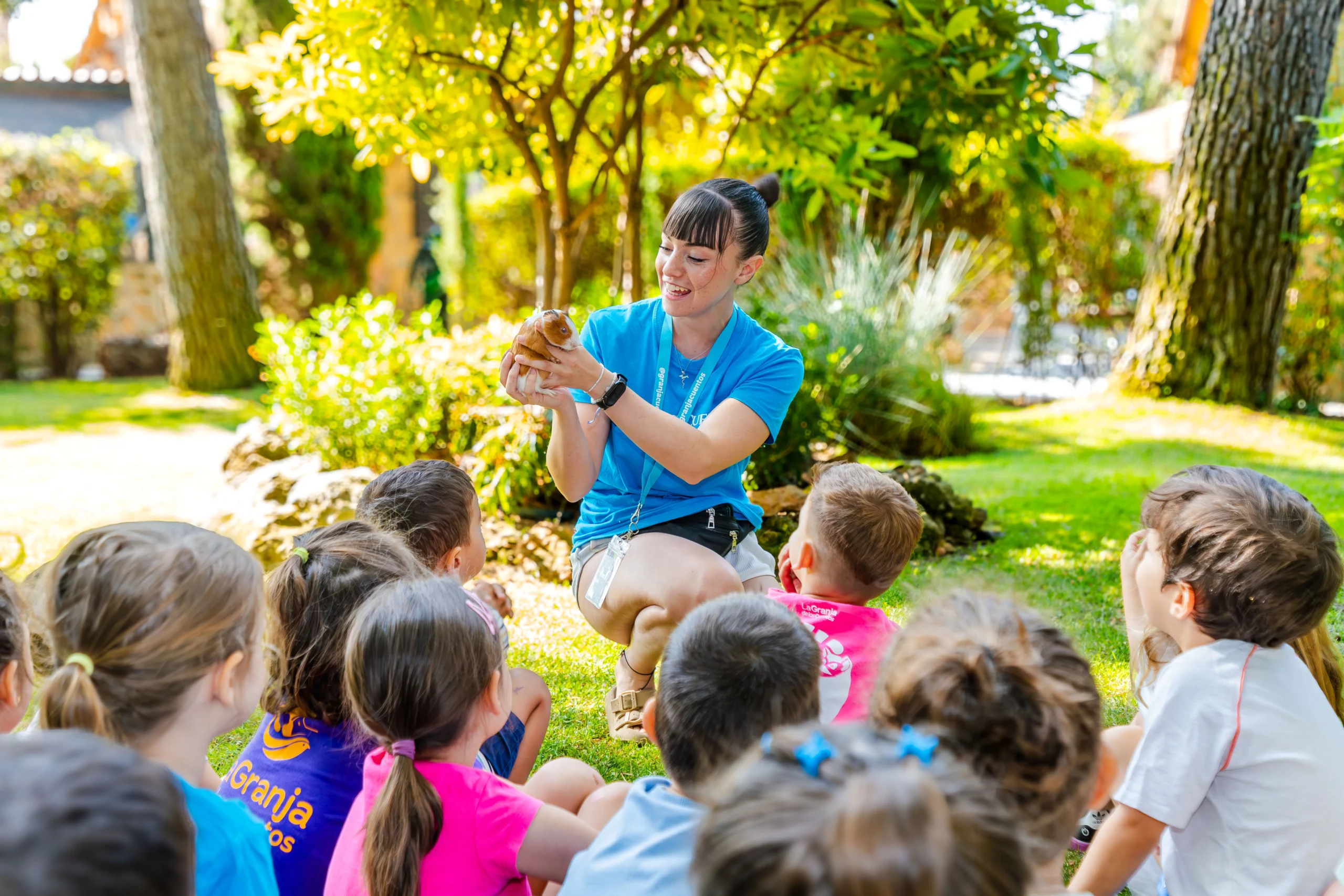 Monitora enseña un pequeño animal a un grupo de niños en La Granja de los Cuentos