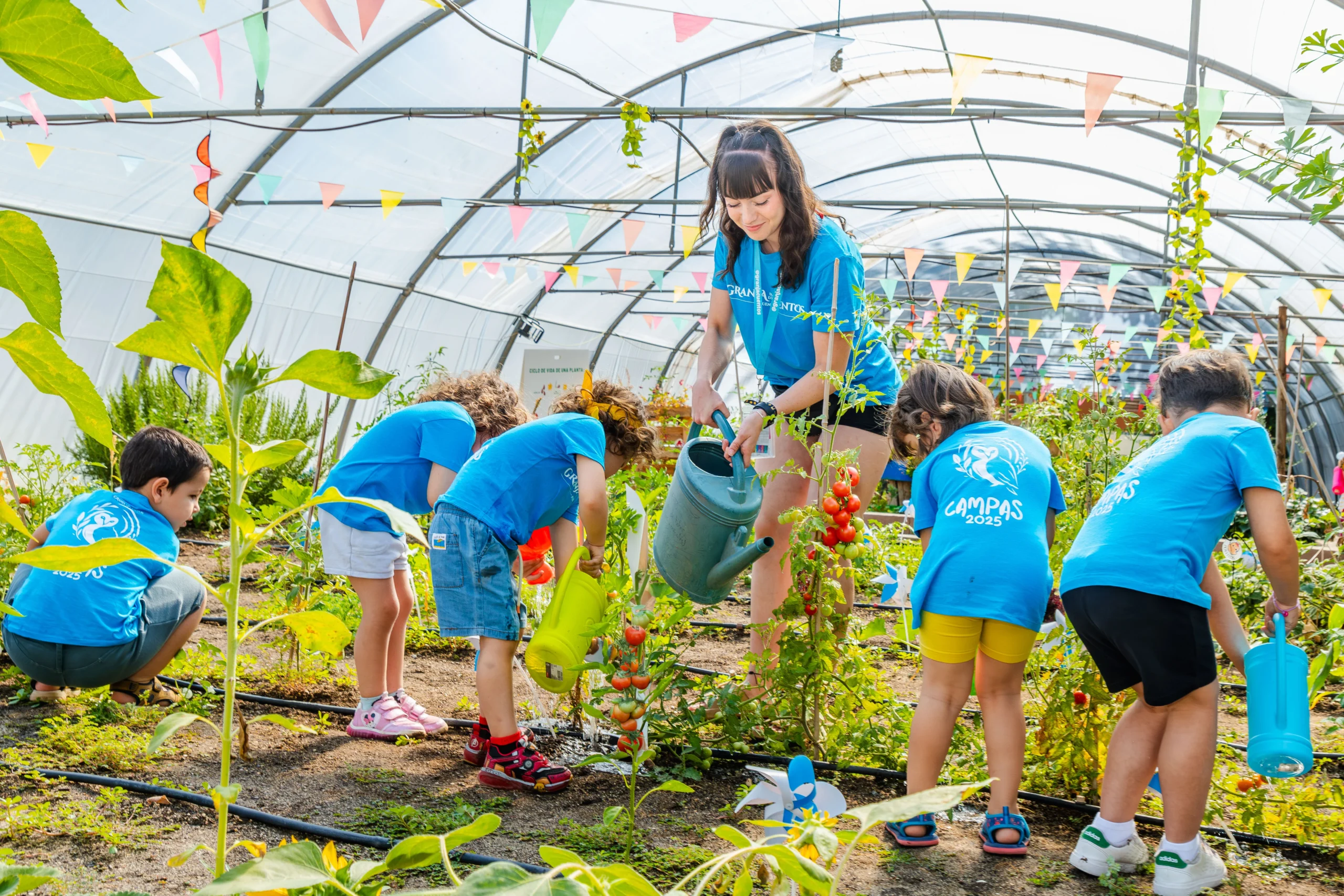 Niños riegan plantas en el invernadero durante una actividad en La Granja de los Cuentos