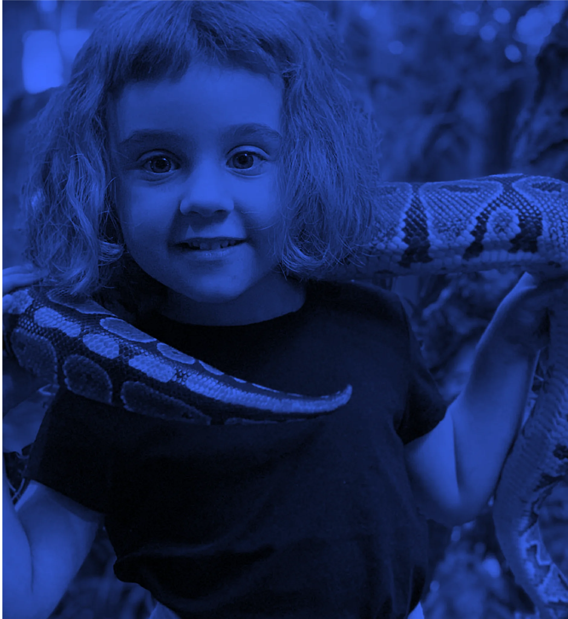 Niño sonriendo con una serpiente sobre los hombros en una actividad educativa.
