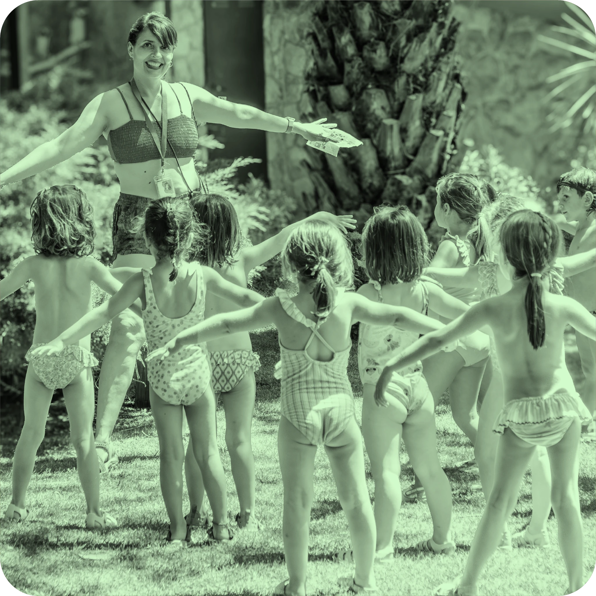 Monitora guiando una actividad al aire libre con niños en bañador durante los campamentos de La Granja de los Cuentos.