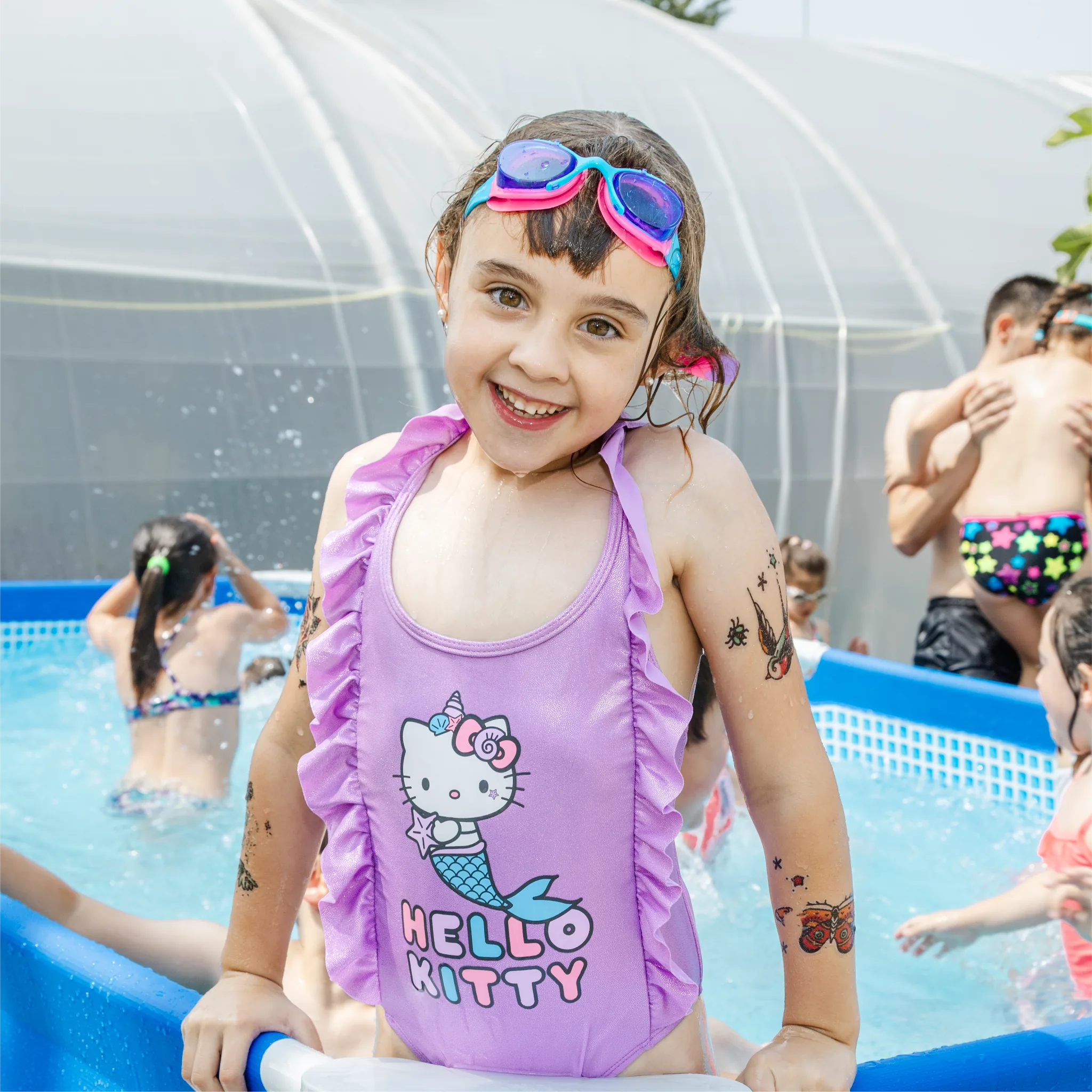 Niña sonriendo en una piscina infantil durante una actividad de agua en los campamentos de La Granja de los Cuentos.