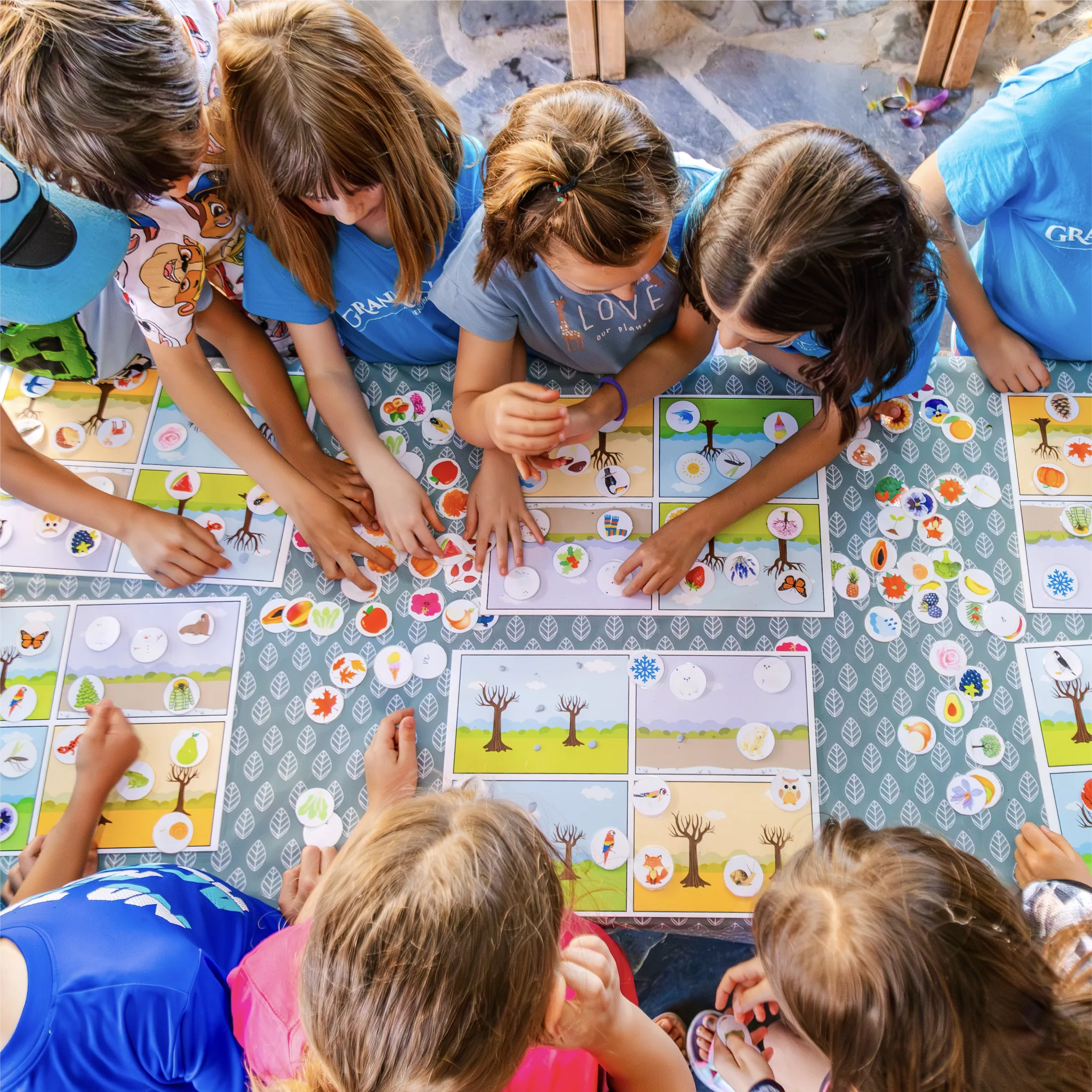 Niños participando en un juego educativo de naturaleza alrededor de una mesa en los campamentos de La Granja de los Cuentos.