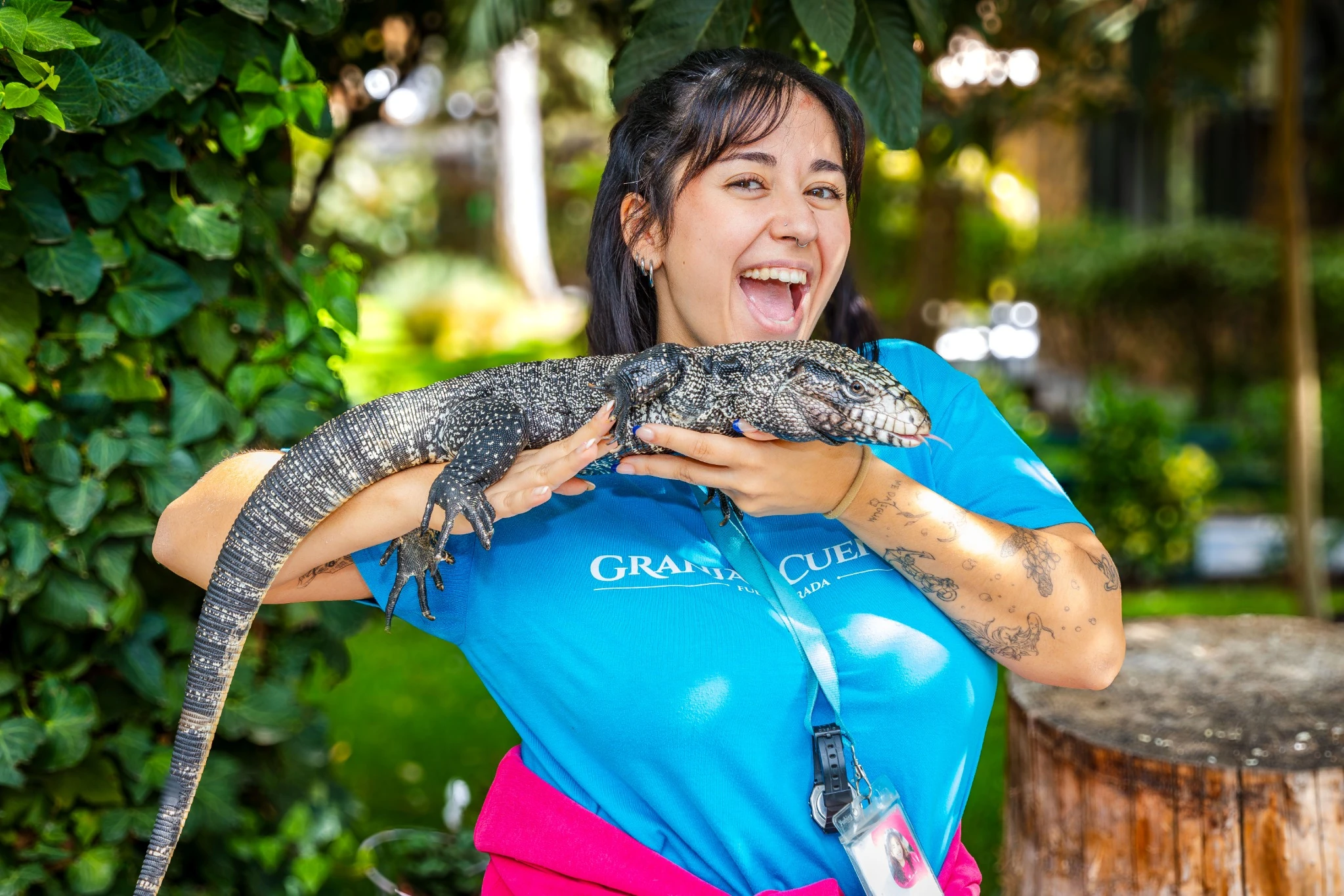 Monitora sosteniendo un gran lagarto durante una actividad con animales en La Granja de los Cuentos.